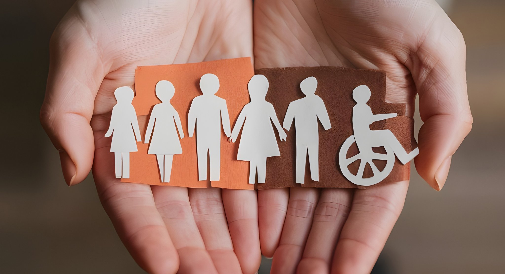 Hands holding paper cutouts of diverse people including a person in a wheelchair, representing inclusion and community